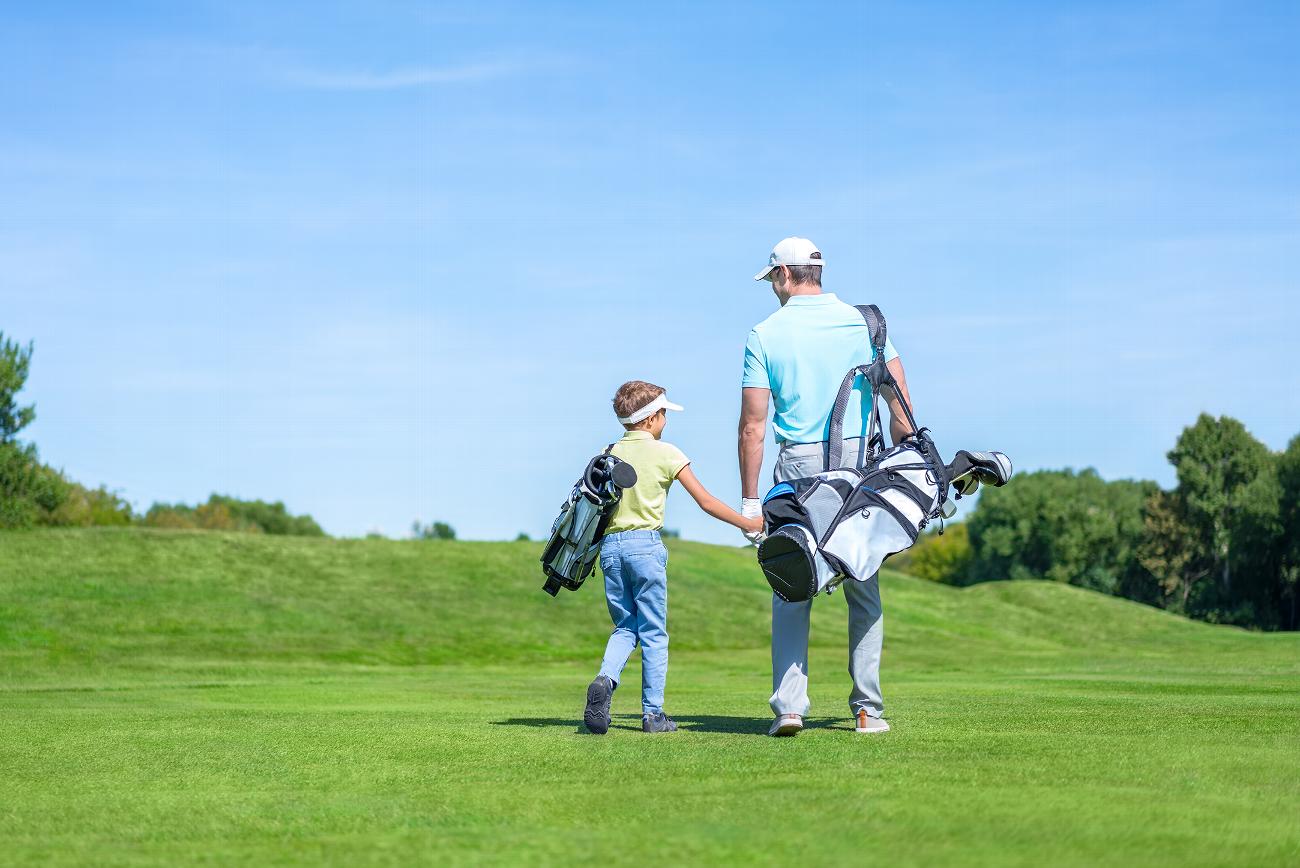 Father and son holding hands on golf course