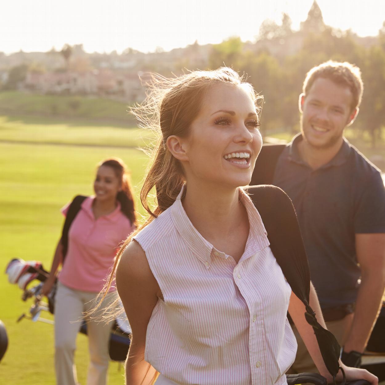 Woman and friends walking with golfing bags